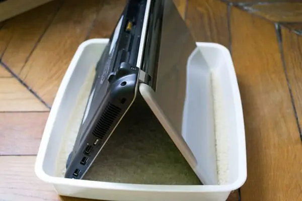 Ordinateur en position renversée dans la boîte avec le riz Ordinateur en position renversée dans la boîte avec le riz